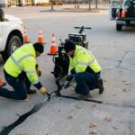 Workers are sealing cracks in a Texas parking lot during a clear December morning.
