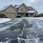 Winter damage to the asphalt driveway caused by snow, ice melt, and standing water